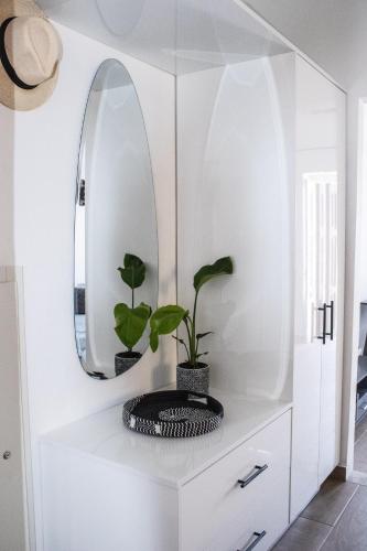 a white dressing room with a mirror and a plant at Duchess Harbour View in Symi