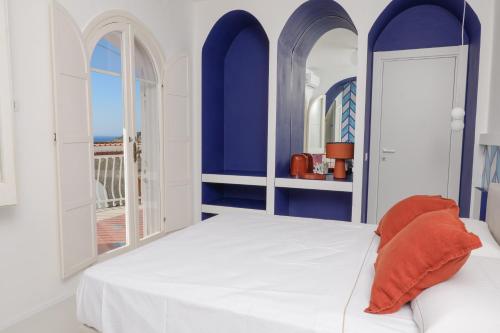 una camera da letto con pareti blu e un letto con un cuscino arancione di La Maison De La Ville a Massa Lubrense