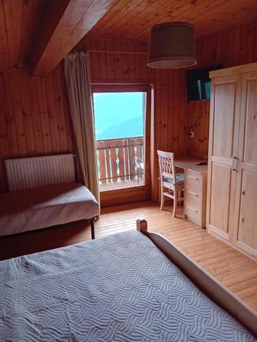 Un dormitorio con una cama y un escritorio y una ventana. en Eggernhof, en Lauregno
