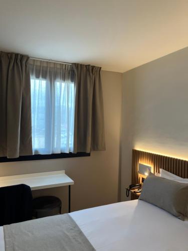 a bedroom with a bed and a desk and a window at Hôtel Le Relais des Brasseurs - Aubagne in Aubagne