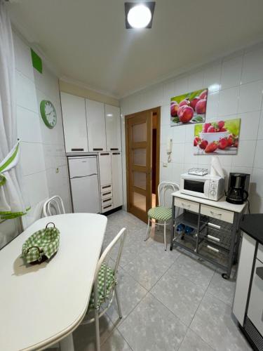 a kitchen with a table and a white table and chairs at Apartamento Arenal in Portonovo