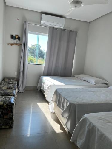 two beds in a room with a window at Casa Tô D`Boa Capitólio in Capitólio