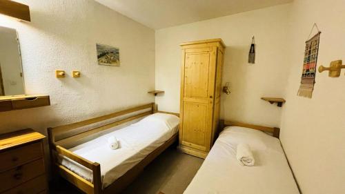 - 2 lits dans une petite chambre avec une porte dans l'établissement Résidence Chasseforet - Appartement 2 pièces 4 personnes situé à Méribel sur la route des Chalets proche des pistes MAE-2107, à Les Allues