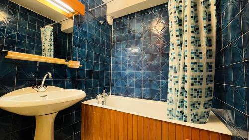 - une salle de bains carrelée de bleu pourvue d'un lavabo et d'un rideau de douche dans l'établissement Résidence Chasseforet - Appartement 2 pièces 4 personnes situé à Méribel sur la route des Chalets proche des pistes MAE-2107, à Les Allues