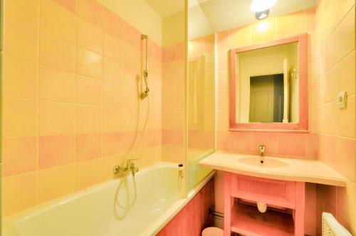 une salle de bain avec un lavabo, une baignoire et un miroir dans l'établissement La résidence du Lac - maeva Home - Appartement 2 pièces 5 personnes - Sélection MAE-8161, à Monflanquin