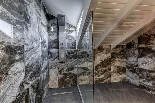 a walk in shower in a room with a stone wall at Oceanis Rooms Apartments in Barbati