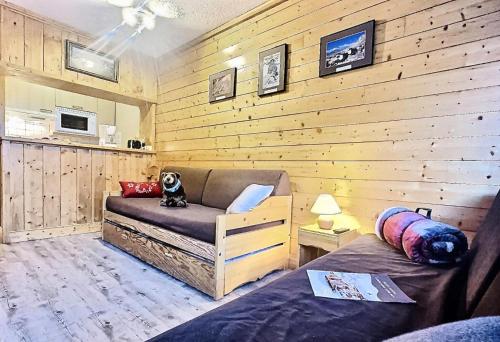 Cette chambre est dotée d'un mur en bois, d'un canapé et d'un lit. dans l'établissement Résidence Le Pramecou - Joli studio 4 personnes à Tignes proche des pistes et des commerces dans le quartier du Val Claret. Appartement situé au 5ème ét MAE-2133, à Tignes