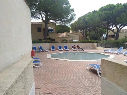 un groupe de chaises longues et une piscine dans l'établissement Résidence Odalys Cap d'Agde - Piscine chauffée, clim, plage, parking privé, terrasse, au Cap d'Agde