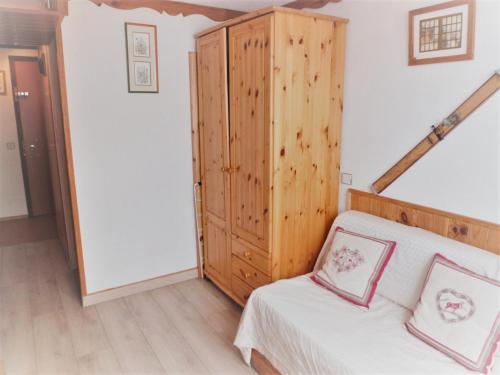 una camera da letto con un letto e un armadio in legno di Résidence Le Palafour - Studio 2 personnes à Tignes au pied des pistes, des commerces, de l'ESF et de l'office du tourisme dans le quartier du lac. Appa MAE-2160 a Tignes