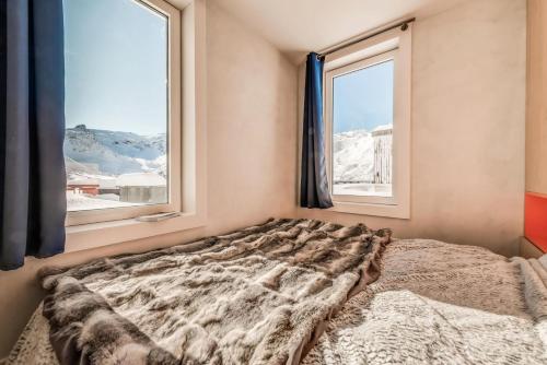 - un lit dans une chambre avec 2 fenêtres dans l'établissement Résidence Palafour - Appartment en duplex 3 - 80m2 - 8 personnes - Toit terrasse MAE-3377, à Tignes