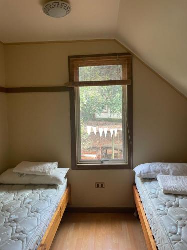 two beds in a room with a window at Cabañas La Leona in Vilches