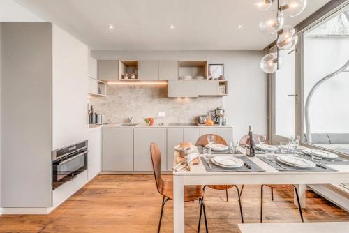 une cuisine blanche avec une table et des chaises dans l'établissement Résidence Combe Folle - Appartement rénové 3 - Terrasse - vue lac MAE-3384, à Tignes