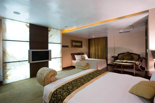 a hotel room with two beds and a television at Crystal Business Motel in Hsinchu City