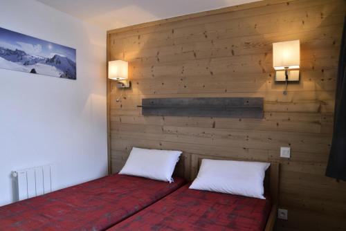 - 2 lits dans une chambre avec un mur en bois dans l'établissement Résidence Saint Jacques A - 5 Pièces pour 11 Personnes 22, à Mâcot La Plagne