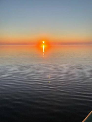 a large body of water with the sun in the distance at Modern Home on Mille Lacs Lake! Amazing yard and game-room! in Garrison