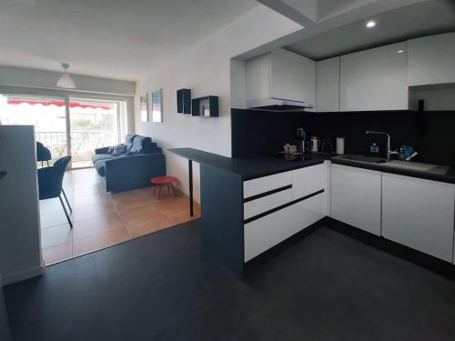 une cuisine avec des armoires blanches et un salon dans l'établissement Nouveau T2 au centre, climatisé, à La Grande Motte