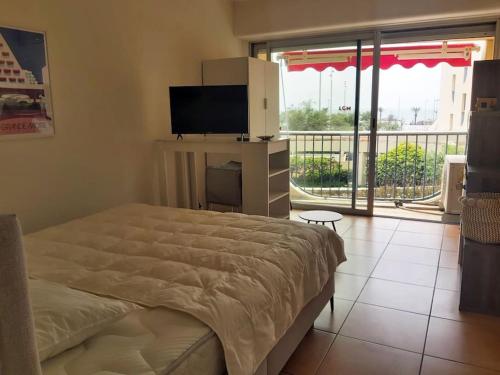 une chambre avec un lit et une télévision et un balcon dans l'établissement Nouveau T2 au centre, climatisé, à La Grande Motte