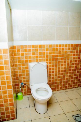 a bathroom with a toilet in a tiled wall at Fleur Guest House in Kigali