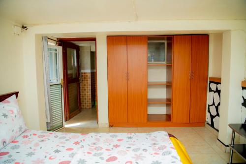 a bedroom with a bed and some wooden cabinets at Fleur Guest House in Kigali