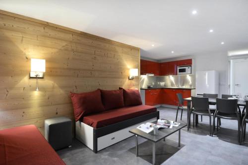 un salon avec un canapé rouge et une cuisine dans l'établissement Résidence Saint Jacques A - 3 Pièces pour 8 Personnes 34, à Mâcot La Plagne