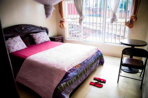 a bedroom with a bed and a window with slippers on the floor at Fleur Guest House in Kigali