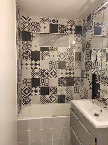 une salle de bain avec une baignoire blanche et un lavabo dans l'établissement Appartement Cosy, 3 Chambres près du centre ville, à Orvault