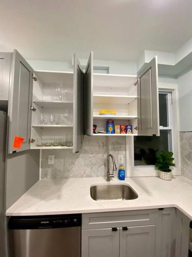 a kitchen with white cabinets and a sink at Heart of NY - 17 min to Empire State & Times Sq in Jersey City