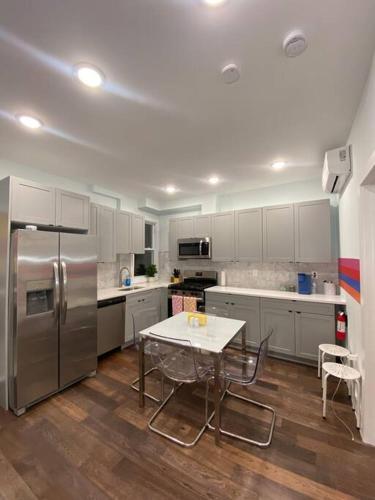 a kitchen with a table and a stainless steel refrigerator at Heart of NY - 17 min to Empire State & Times Sq in Jersey City
