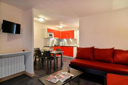 un salon avec un canapé rouge et une cuisine dans l'établissement Résidence Saint Jacques A - 2 Pièces pour 5 Personnes 09, à Mâcot La Plagne