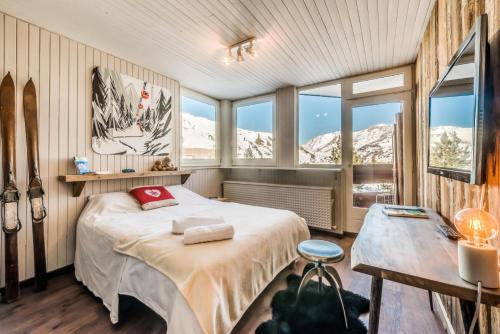 a bedroom with a bed and a table and windows at Résidence Roches Rouges A - Pied de pistes, appartement chaleureux et douillet MAE-3523 in Tignes