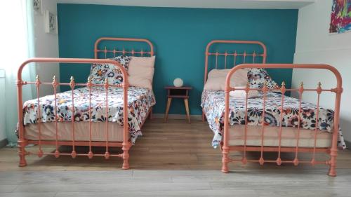 - 2 lits dans une chambre avec un mur bleu dans l'établissement Maison de village avec sa charmante petite cour intérieure, à Fleury