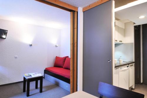 Cette petite chambre comprend un canapé rouge et une table. dans l'établissement Résidence Les Glaciers 3 - Studio pour 4 Personnes 29, à Mâcot La Plagne