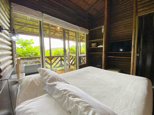 a bedroom with a white bed and a window at Horizon Hotel & Yoga Center in Santa Teresa Beach
