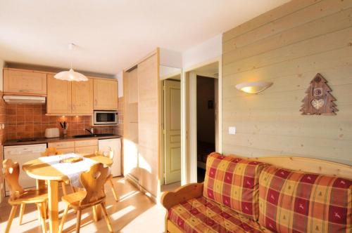 Il dispose d'une cuisine et d'un salon avec une table et un canapé. dans l'établissement Résidence Aigue-marine - 2 Pièces pour 5 Personnes 82, à Mâcot La Plagne