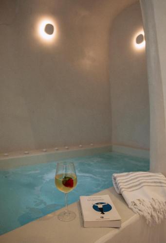 a glass of wine sitting next to a swimming pool at Utopia Suites Santorini in Karterados
