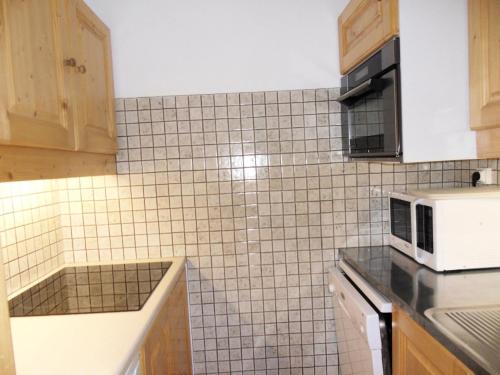 Il comprend une cuisine dotée d'un mur en carrelage blanc et d'un four micro-ondes. dans l'établissement Résidence Carroley B - 2 Pièces pour 5 Personnes 91, à Mâcot La Plagne