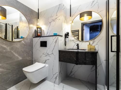 a bathroom with a toilet and a sink and mirrors at ApartPort nowoczesne apartamenty in Gdynia