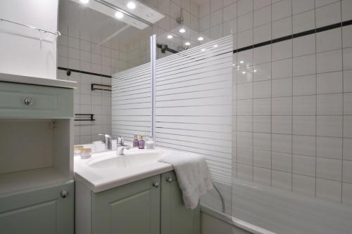 une salle de bain blanche avec un lavabo et une douche dans l'établissement Résidence Carroley B - 2 Pièces pour 5 Personnes 97, à Mâcot La Plagne