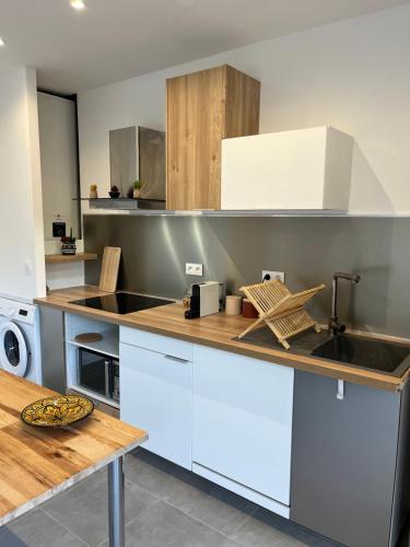 une cuisine avec des armoires blanches et un comptoir en bois dans l'établissement Résidence les Moulins-appartements privatifs, à Olmeto