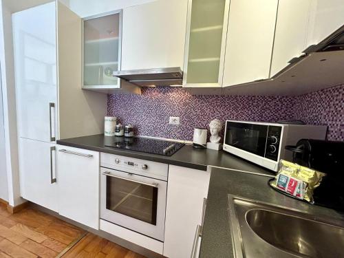 eine Küche mit weißen Schränken und einer Spüle und einer Mikrowelle in der Unterkunft Kibilù - Via Morosini - Policlinico - Centro Città in Mailand