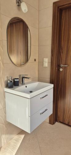 a bathroom with a white sink and a mirror at Karmelowy Zakątek in Darłowo