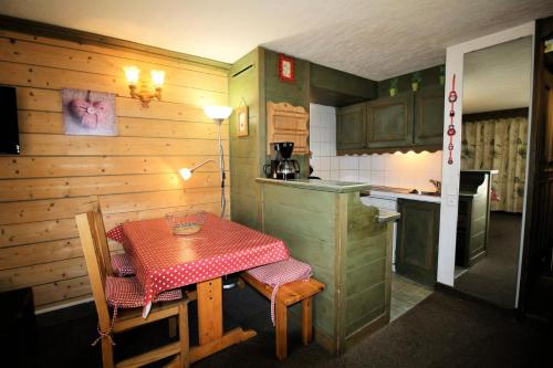 une petite cuisine avec une table et un chiffon rouge dans l'établissement Résidence Palafour - Studio chaleureux, terrasse vue lac MAE-3615, à Tignes