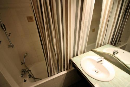 une salle de bain avec un lavabo et un rideau de douche dans l'établissement Résidence Palafour - Studio chaleureux, terrasse vue lac MAE-3615, à Tignes