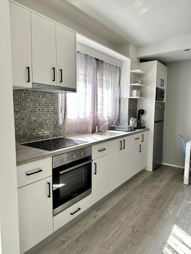 a kitchen with white cabinets and stainless steel appliances at Athena Apartment in Argostoli