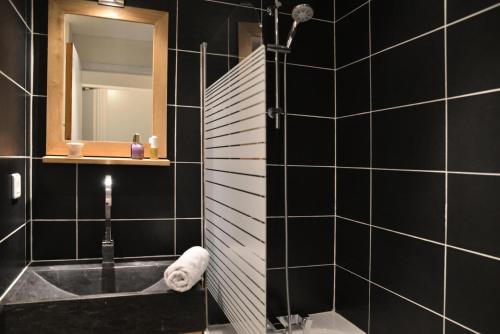 une salle de bain noire avec un lavabo et un miroir dans l'établissement Résidence Themis - Studio pour 4 Personnes 30, à Mâcot La Plagne