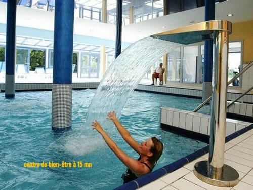 une femme est sous une fontaine d'eau dans une piscine dans l'établissement Gîte et Grange à Jeux du Bonhomme Bouton, à Guinzeling