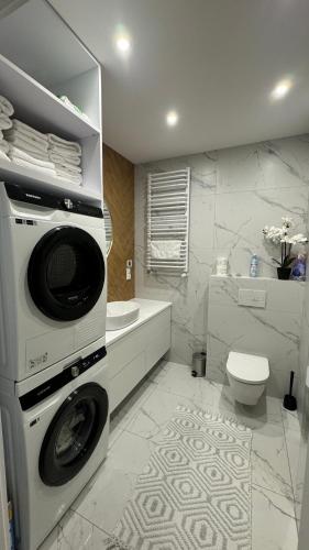 a bathroom with a washing machine and a toilet at Nowoczesny Apartament Tatarska in Przemyśl