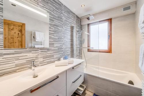 une salle de bain avec un lavabo, une baignoire et un miroir dans l'établissement Résidence Ducs De Savoie - Appartement 3, proche des pistes,commerce, vue lac MAE-3644, à Tignes