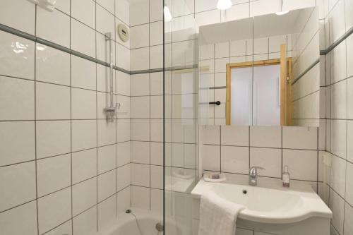 La salle de bains est pourvue de carrelage blanc, d'un lavabo et d'une douche. dans l'établissement Résidence Themis - 2 Pièces pour 6 Personnes 63, à Mâcot La Plagne
