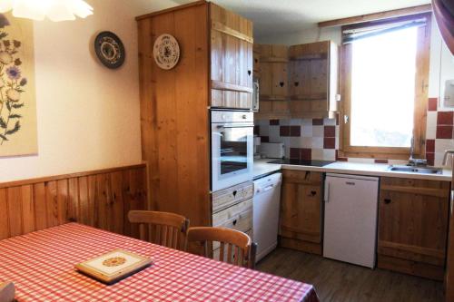 une cuisine avec des placards en bois et une table avec un chiffon de table dans l'établissement Résidence Aigue-marine - 2 Pièces pour 5 Personnes 78, à Mâcot La Plagne